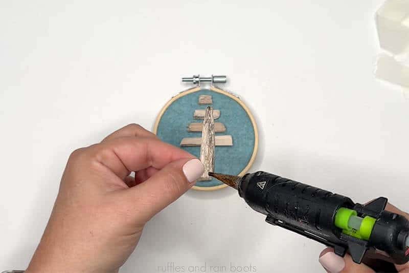 Crafter adding each driftwood Christmas tree piece onto felt with hot glue.
