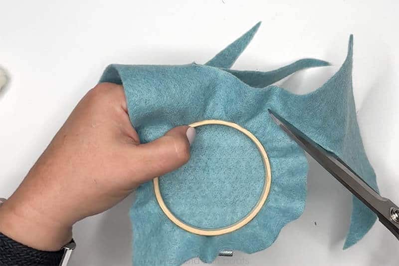 Crafter trimming the back of the embroidery hoop felt to finish the backing.