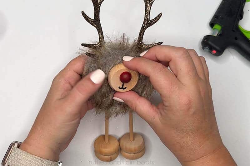 Crafter gluing on a reindeer face with a bright red nose.