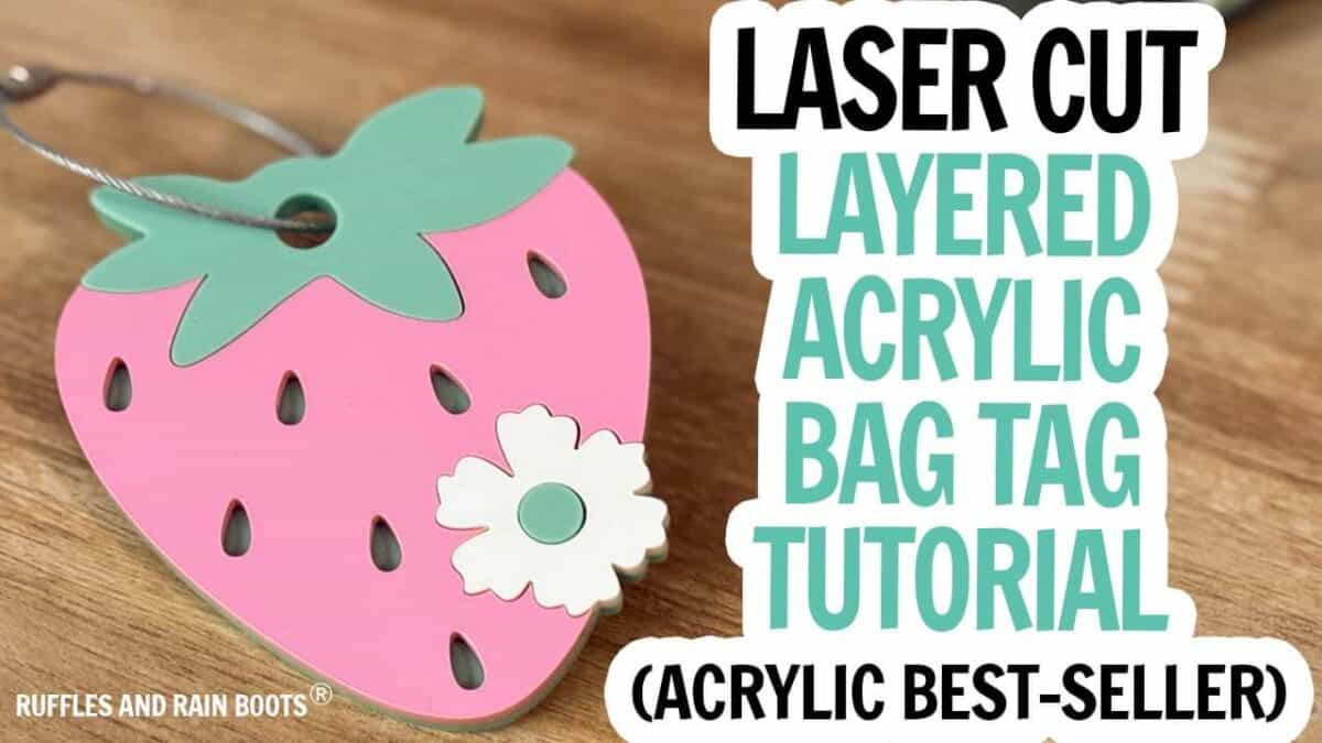 Horizontal image in YouTube thumbnail style with a strawberry and blossom and text which reads laser cut layered acrylic bag tag tutorial.