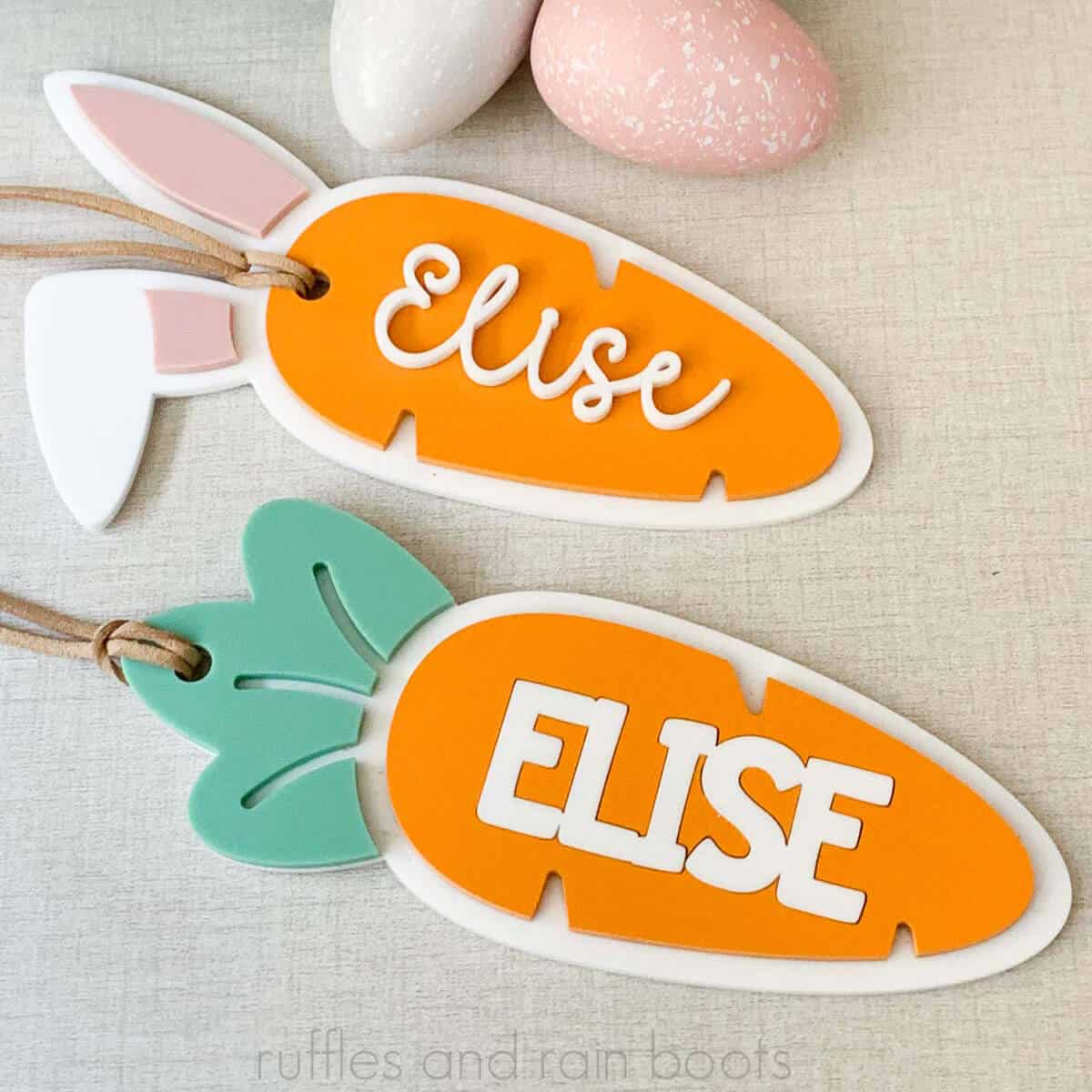 Close up square image of orange, white, green, and pink acrylic basket tags in carrot shapes with names.