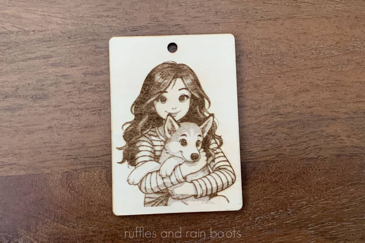 Horizontal image of a little girl holding a Husky puppy dog engraved onto a wood tag using the TOOCAA NOVA laser.
