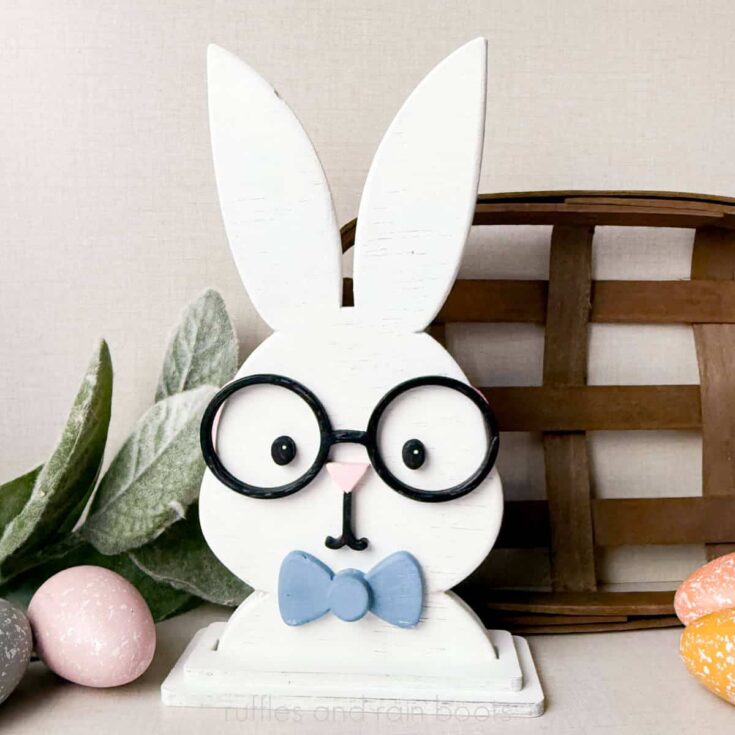 Square, close up image of a laser cut boy bunny with a bow tie shelf sitter on an Easter holiday background.