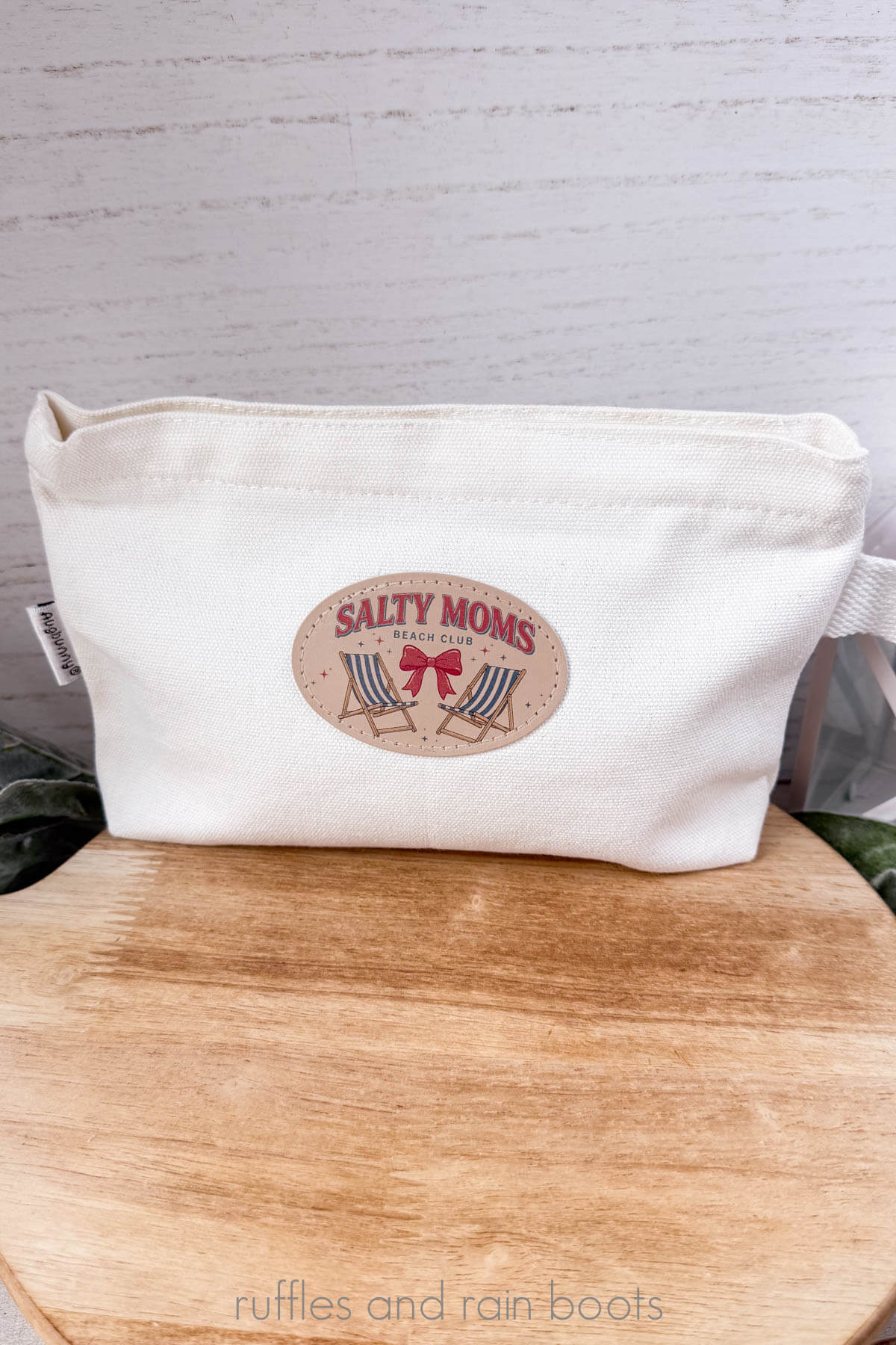 A printed PU Leather patch made with the xTool M2 heat pressed onto a white makeup bag on a round block of wood.