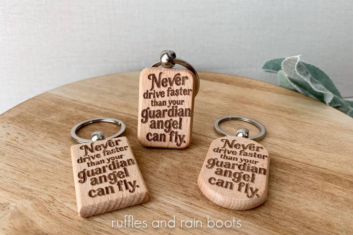 Horizontal, close up view of three laser engraved keychains with the words, "Never drive faster than your guardian angel can fly."
