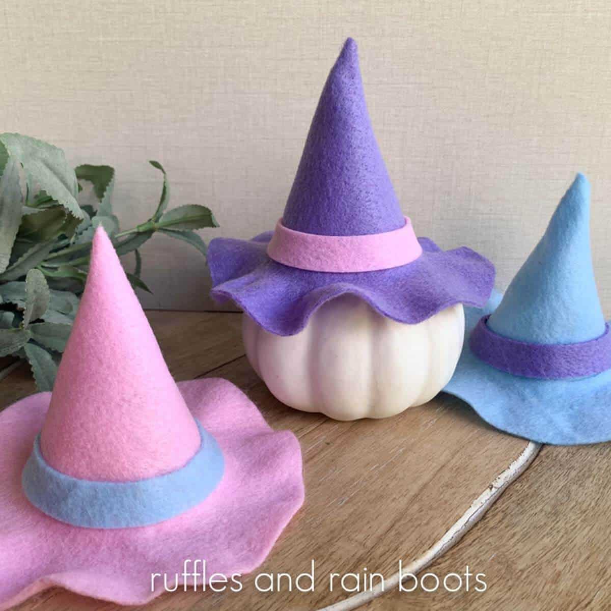 Close up square image of three pastel Halloween mini witch hats with bands made from felt.