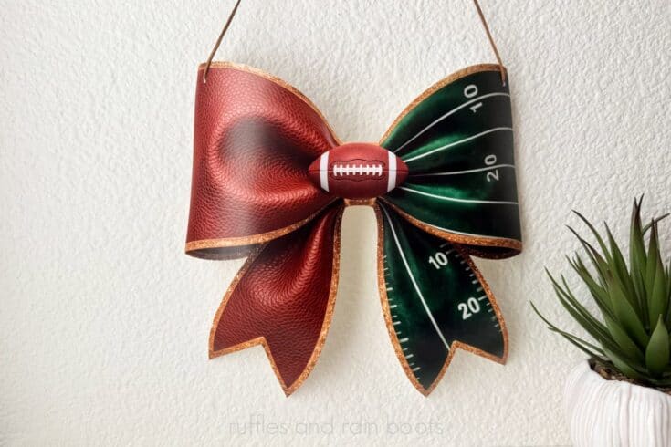UV printed football bow sign for football season with faux leather, velvet ribbon yard lines, and football accent hanging on a wall.