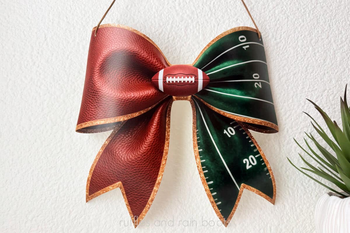 Close up horizontal image of a football bow sign made with the xTool O1 UV printer, a CO2 laser, and the xTool WonderPress for an adorable football season design.