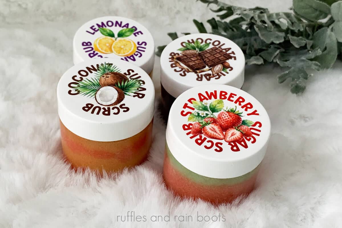 Horizontal close up image of four scents and combinations of a DIY 5 minute sugar scrub recipe with original label art on a white furry background with greenery.